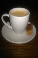 A generic mug of coffee, on a saucer, with a biscotti to one side