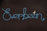 Everbean written in a cursive script, blue on brown, with the outline of a bird on the a