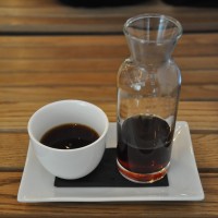 An Ethiopian Duromina from Workshop at Sharps Coffee Bar, beautifully presented in a glass carafe and a white, handless cup on a white china tray.