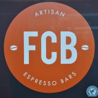 The FCB Logo: the letters "FCB" in white in the centre of an orange circle, with "Artisan Espresso Bars" in white around the circumference.