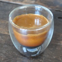 A double espresso shot from the Brooklyn Roasting Company, freshly pulled, in a thermally-insulated shot glass. The fully developed crema will soon dissipate.