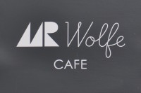 The words Mr Wolfe Cafe in white on black taken from the side of the building.