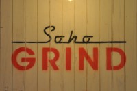 The Soho Grind logo from the back wall of Soho Grind: the word Soho written in black script over GRIND in red capitals.