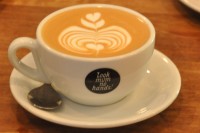A flat white, with lovely latte art, in a classic white bowl cup, with the Look Mum No Hands! logo on the front