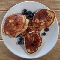 Four mini-American pancakes, in a clover-leaf arrangement, seen from above.