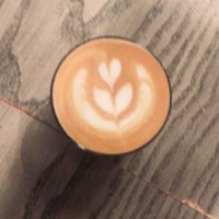 A flat white in a glass from Mother's Milk as seen from above with a simple tulip motif.