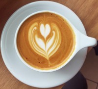 A flat white, seen from above, with tulip pattern latte art in a white cup on a white saucer.