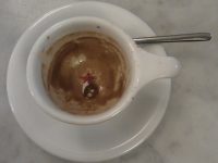 The remains of a shot of Intelligentsia's Black Cat espresso, as seen from above. A five-pointed red star can just be seen at the bottom of the cup, a classic white espresso cup with a big handle.