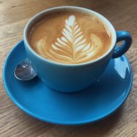 A flat white in a blue cup, with some excellent fern-leaf latte art from the Urban Larder in Cambridge.