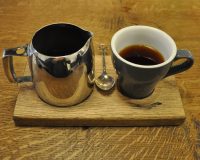 A beautifully-presented filter coffee at TAP, Russell Square, served on a wooden tray with the coffee in a metal jug and a tulip cup on the side.