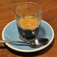 An espresso in a glass, served on a blue saucer at March Coffee, Exeter.