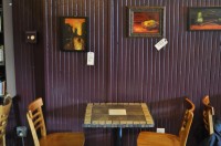 One of the many fine tables in True Grounds, with some of Maria Marx's paintings hanging on the wall above it.