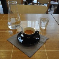 A very fine espresso in a hard to photograph black cup from Coutume, complete with carafe of water.