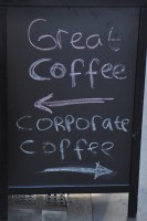 The A-Board from The Fleet Street Press: a hand-written sign say "Great coffee" with an arrow pointing towards the coffee shop and another arrow, pointing the other way, labelled "Corporate coffee".