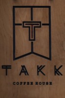 Detail from the TAKK sign which hangs outside on Tariff Street: the TAKK logo, a cut-out T over the words "TAKK Coffee House", etched in wood in black .