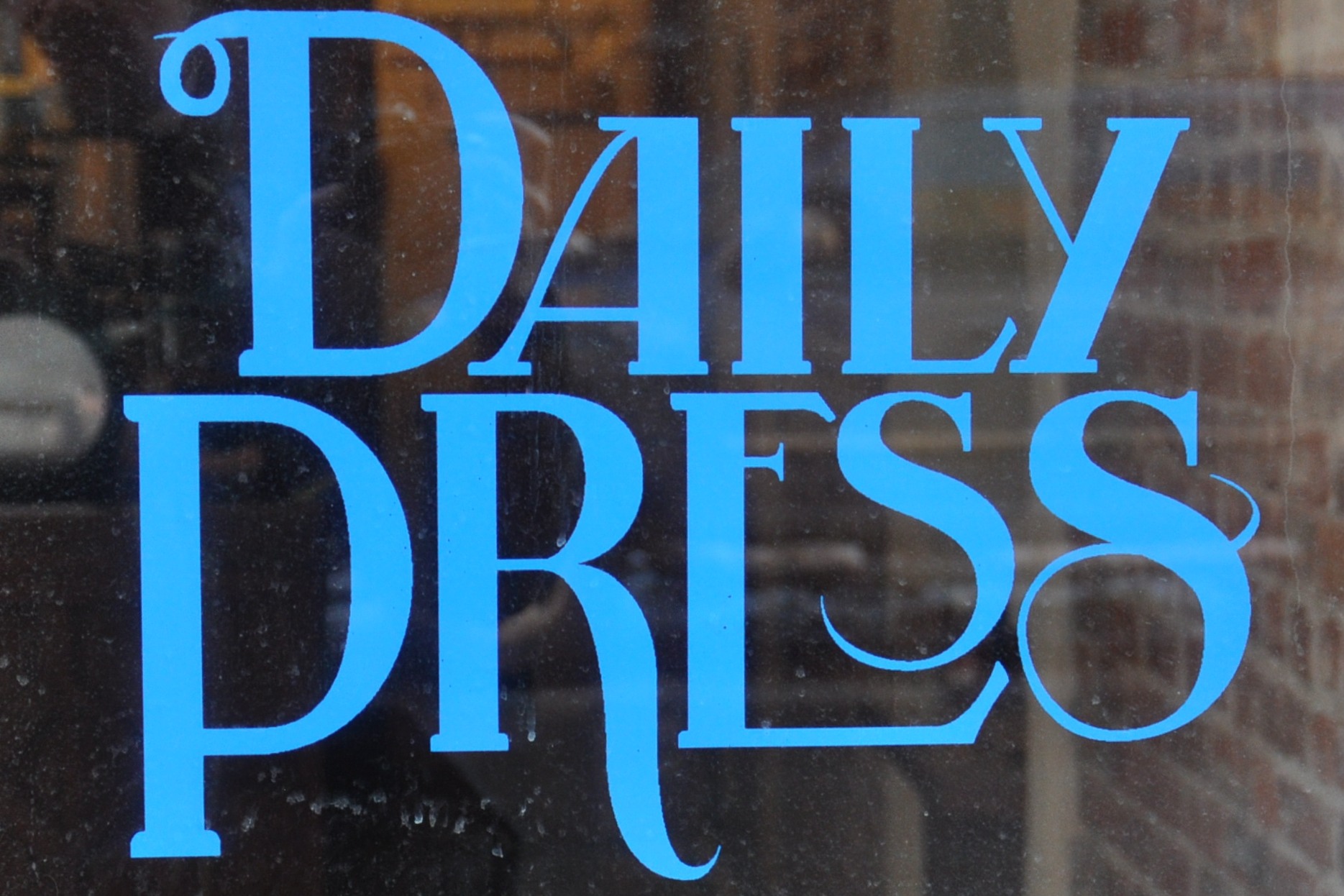 From the window of Daily Press Coffee: the words "Daily Press" written in blue in serif capitals.