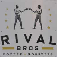 Two bare-chested men, dressed as old-fashioned pugilists, but each holding a large coffee cup in their hands.