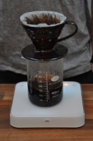 A V60 at Foundry Coffee Roasters, standing on a glass beaker half full of coffee, all on a set of scales.