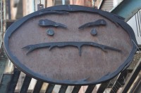 The somewhat unwelcoming Cafe Grumpy sign: an elongated oval, stylised as a face, with frowning eyebrows and a downturned mouth.