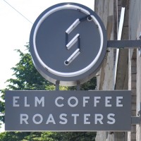 The Elm Coffee Roasters sign, hanging outside on a sunny Seattle day.