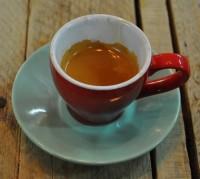 A classic espresso in a red cup on a green saucer.