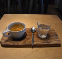 My single-origin Ethiopian Yirgacheffe, a washed coffee from the Negele Gorbitu co-operative, roasted and served by Beanberry Coffee in an over-sized cup on a wooden tray, a glass of water on the side.