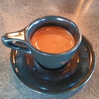 An espresso, made with the Mic Check blend, on the Modbar at Five Watt, East Hennepin, and served in a classic black cup with an oversized handle.