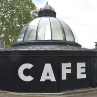The word CAFE in white on the side wall of the Pavilion Cafe in Victoria Park, glass dome soaring above.
