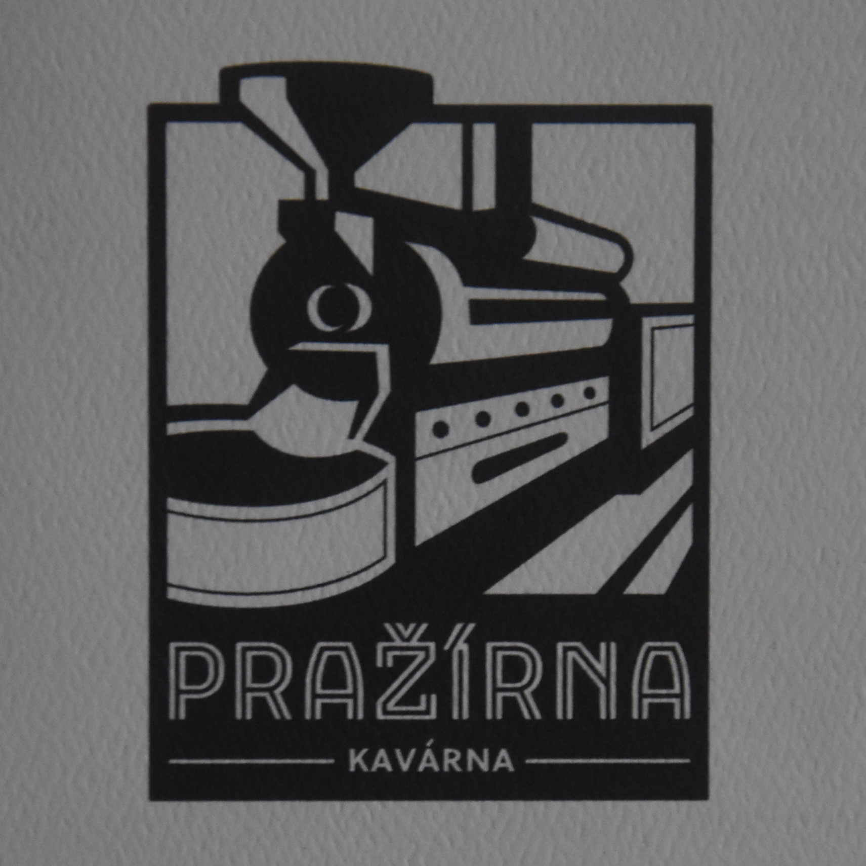 The Pražírna Kavárna logo, a black and white line drawing of a roaster. Am I the only one who thinks it looks like a steam train?