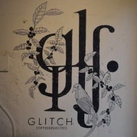 The Glitch Coffee & Roasters logo from the wall next to the roaster.