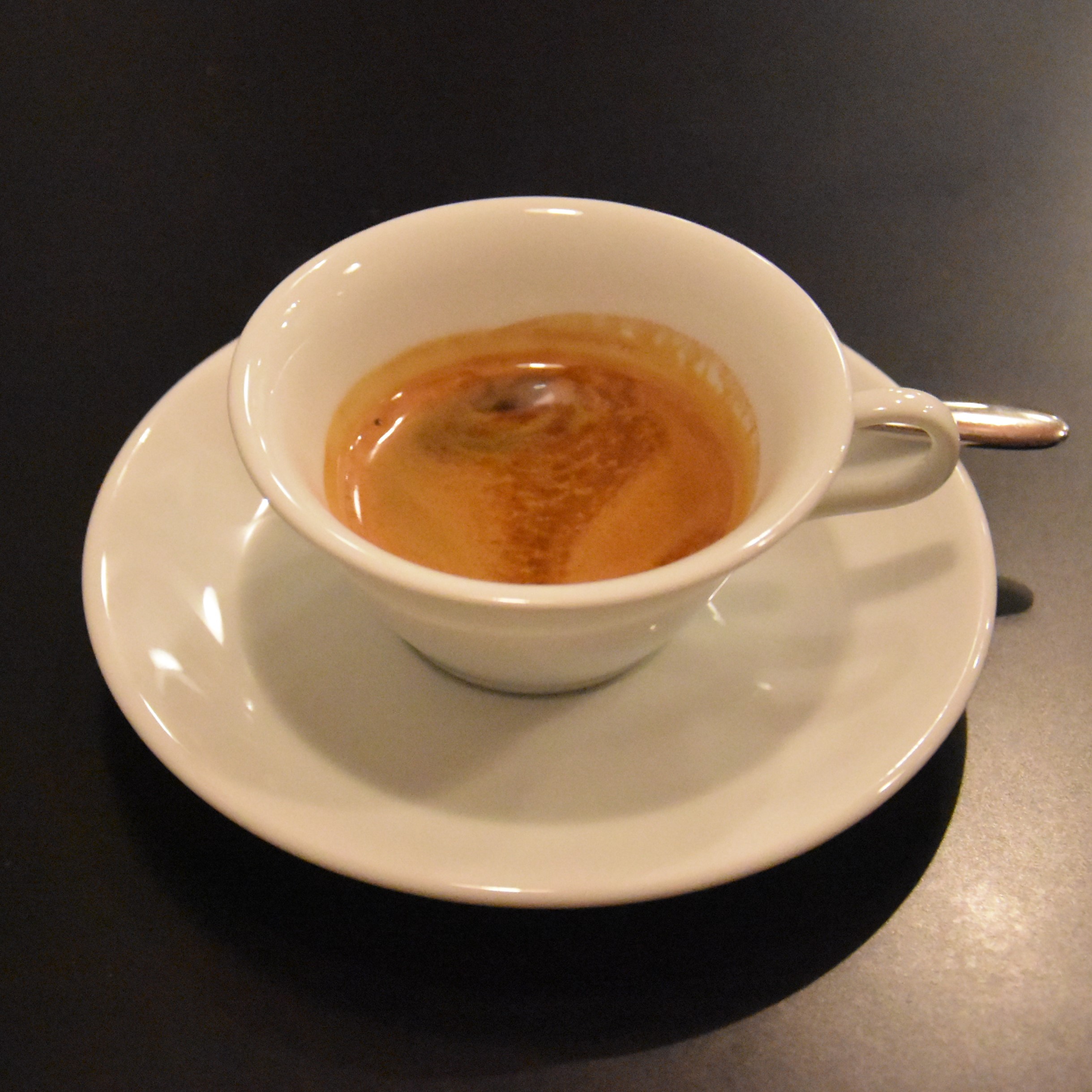 A single-origin espresso served in a wide-brimmed demitasse cup at Maruyama Single Origin in Aoyama, Tokyo, part of an espresso set where the same coffee is served in two different cups.