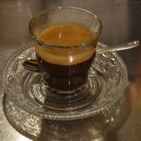 A lovely espresso, made with the house-blend at Blue Monday in Kanazawa and served in a glass, on a patterned glass saucer.