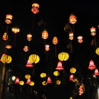 Multi-coloured lanterns hanging in a street in the Old Town in Hoi An and lit up at night.