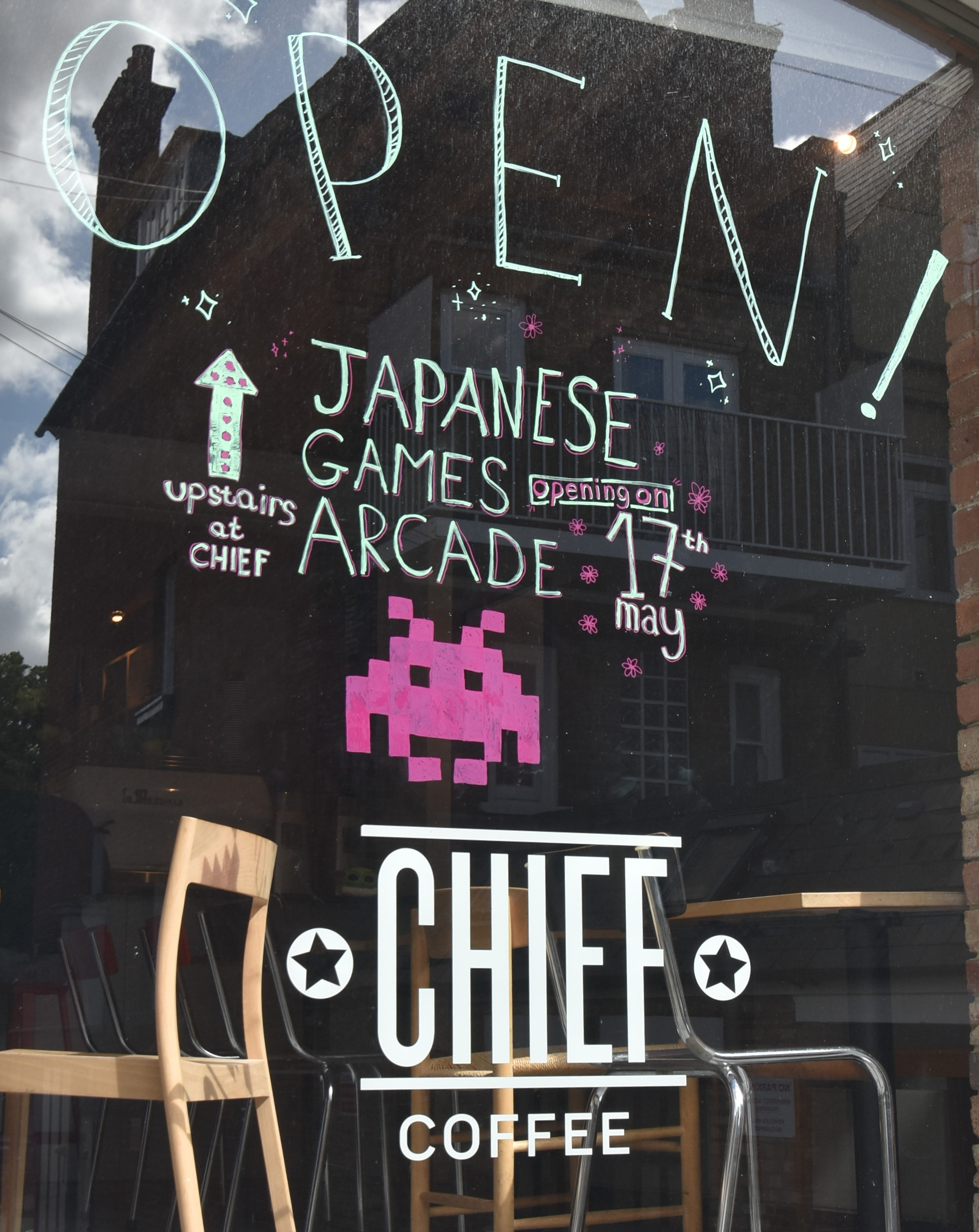 The front window of Chief Coffee celebrating the opening of the Japanese games arcade on the top floor.