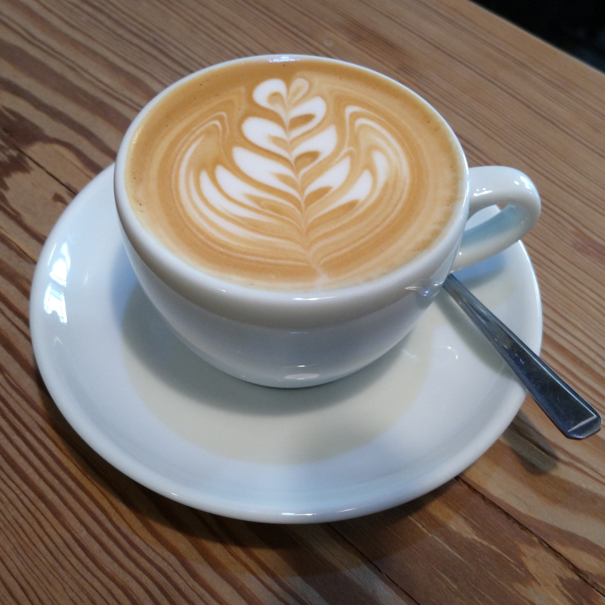 A flat white, with some lovely latte art, served in a classic white cup at Sam's Coffee in Llangollen.