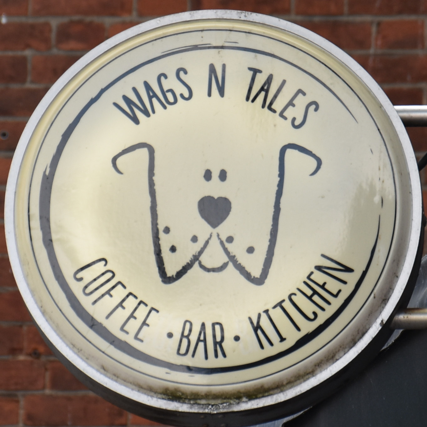 The Wags N Tails logo, a stylised line drawing of a dog's face inside a circle, with the words "Wags N Tales" written at the top of the circle and "Coffee Bar Kitchen" written at the bottom.
