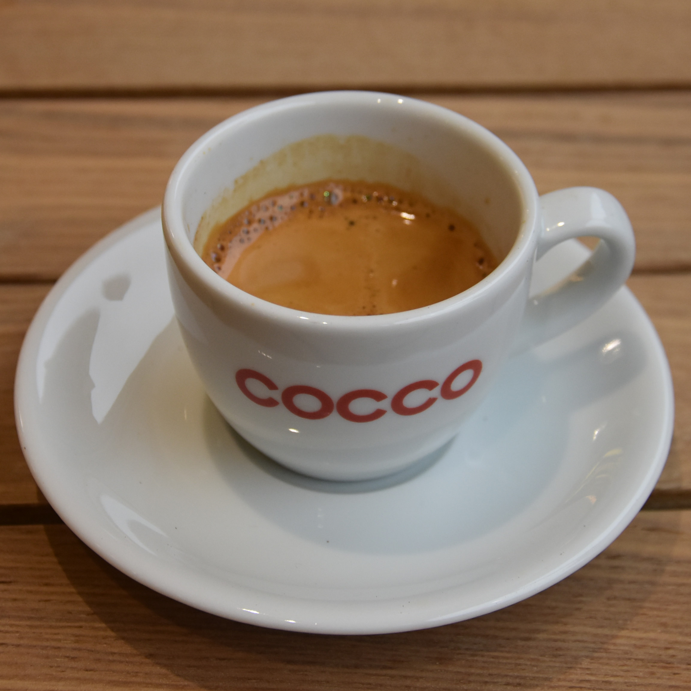 An espresso, made with the Red Brick blend from Square Mile, served in a classic white cup with "Cocco" on the side in red at Cocco Patisserie & Coffee.