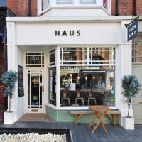 The front of Haus, on Penrhyn Road in Colwyn Bay, with the door on the left and a solitary bench in front of the window on the right.