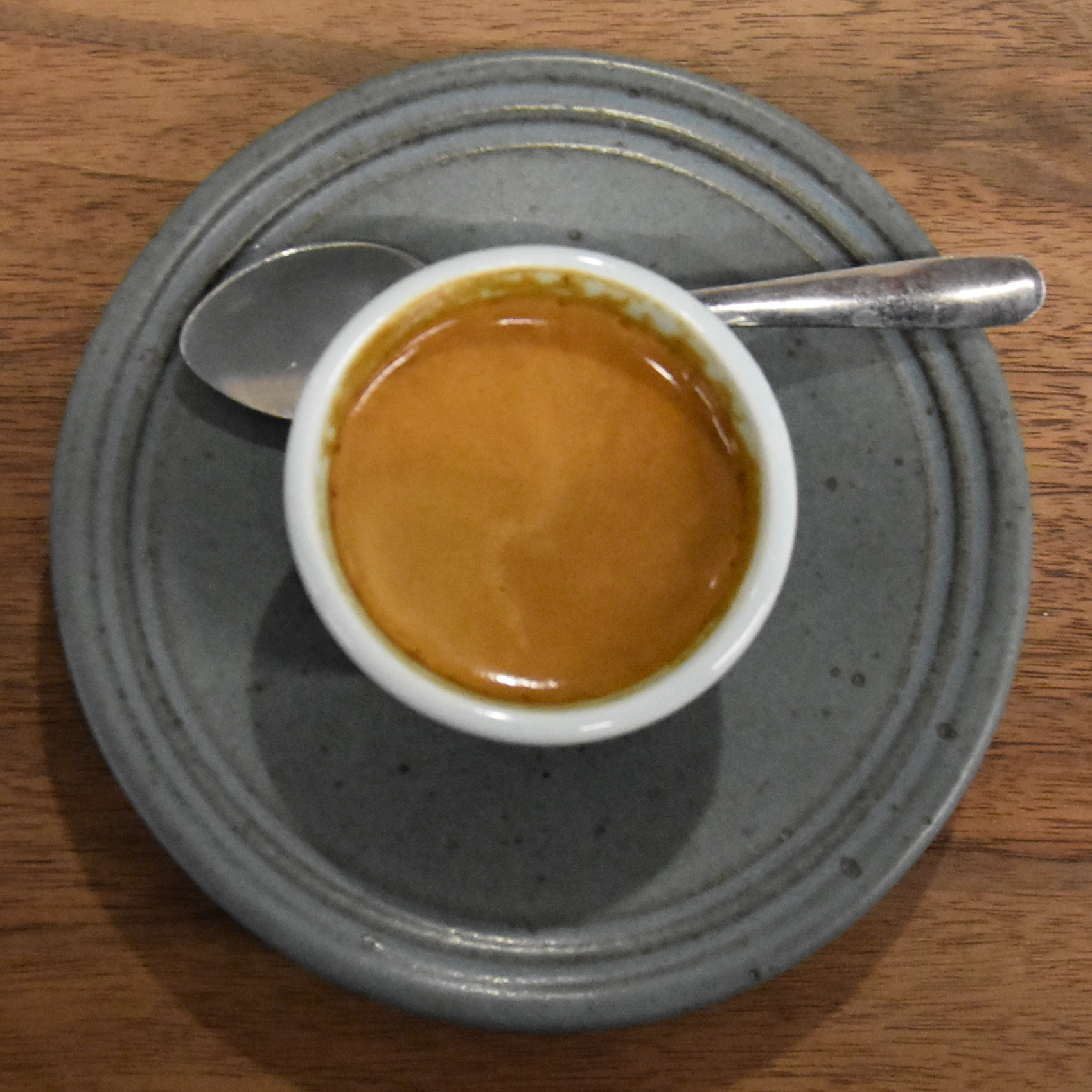 A lovely espresso, made with the Alpha blend, seen from directly above in a handleless ceramic cup and matching saucer, served at Gracenote Coffee and Wine Bar in High Street Place, Boston.