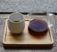 A V60 of the Radiophare, a naturally-processed coffee from Indonesia, served in a carafe with a cup on the side, all presented on a wooden tray.