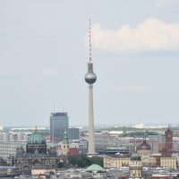 A view across Berlin from Potsdamer Platz to the Berliner Fernsehturm in Alexanderplatz, with the Berliner Dom in the foreground to the left, the spire of St. Marienkirche between them. Meanwhile, to the right, the tower of the Französische Friedrichstadtkirche in Gendarmenmarkt is in the foreground to the right, with the dome of the Humboldt Forum behind that, while to the right of the Humboldt Forum is the red brick clock tower of the Rotes Rathaus (City Hall).