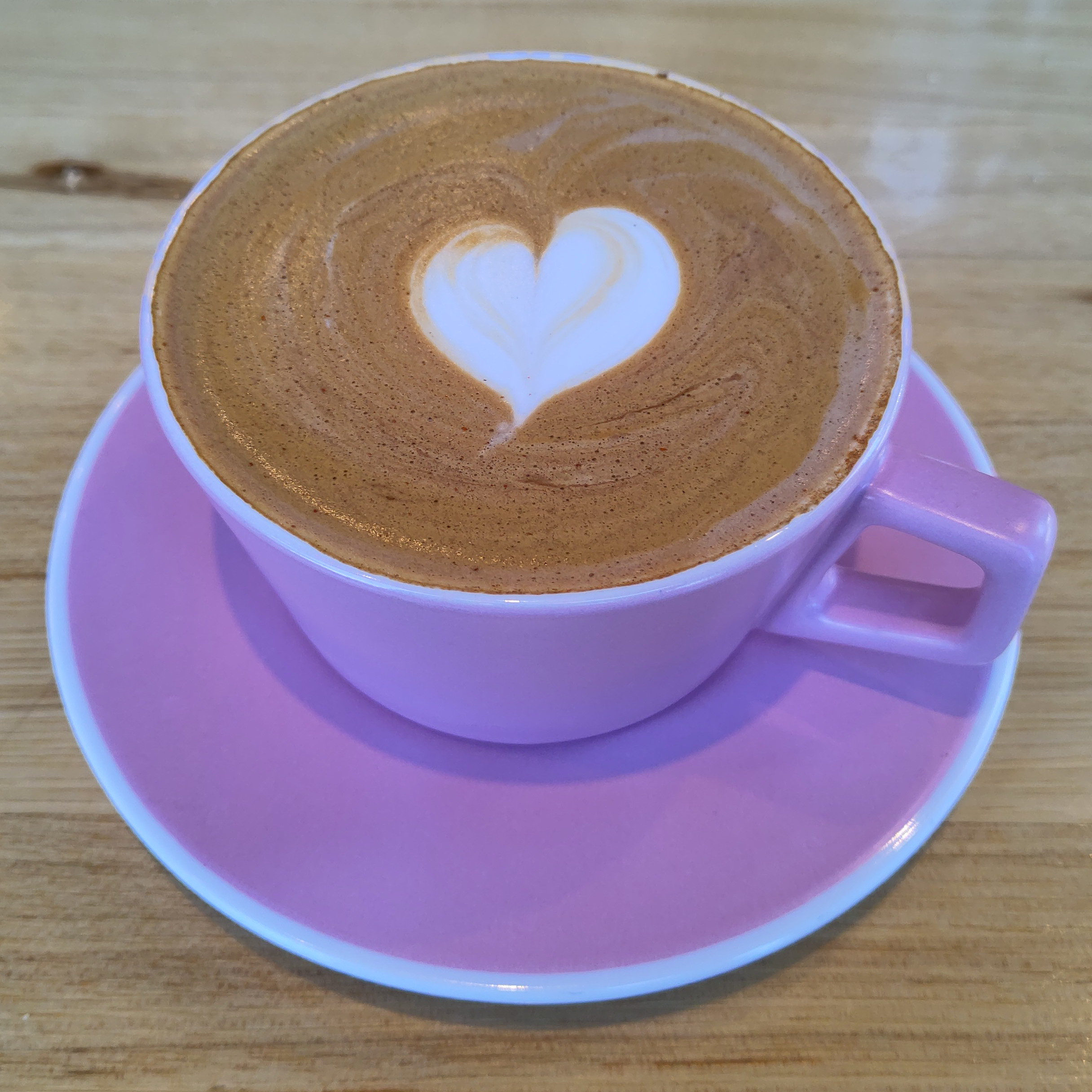 One of Voyager Craft Coffee's signature desintation drinks, the Santiago, served in a large, purple cup with a small latte art heart.