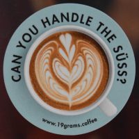 Details from a sticker on the espresso machine at 19grams Alex in Berlin. A flat white, seen from above, with the words "Can you handle the Süss?" written around the rim of the saucer.