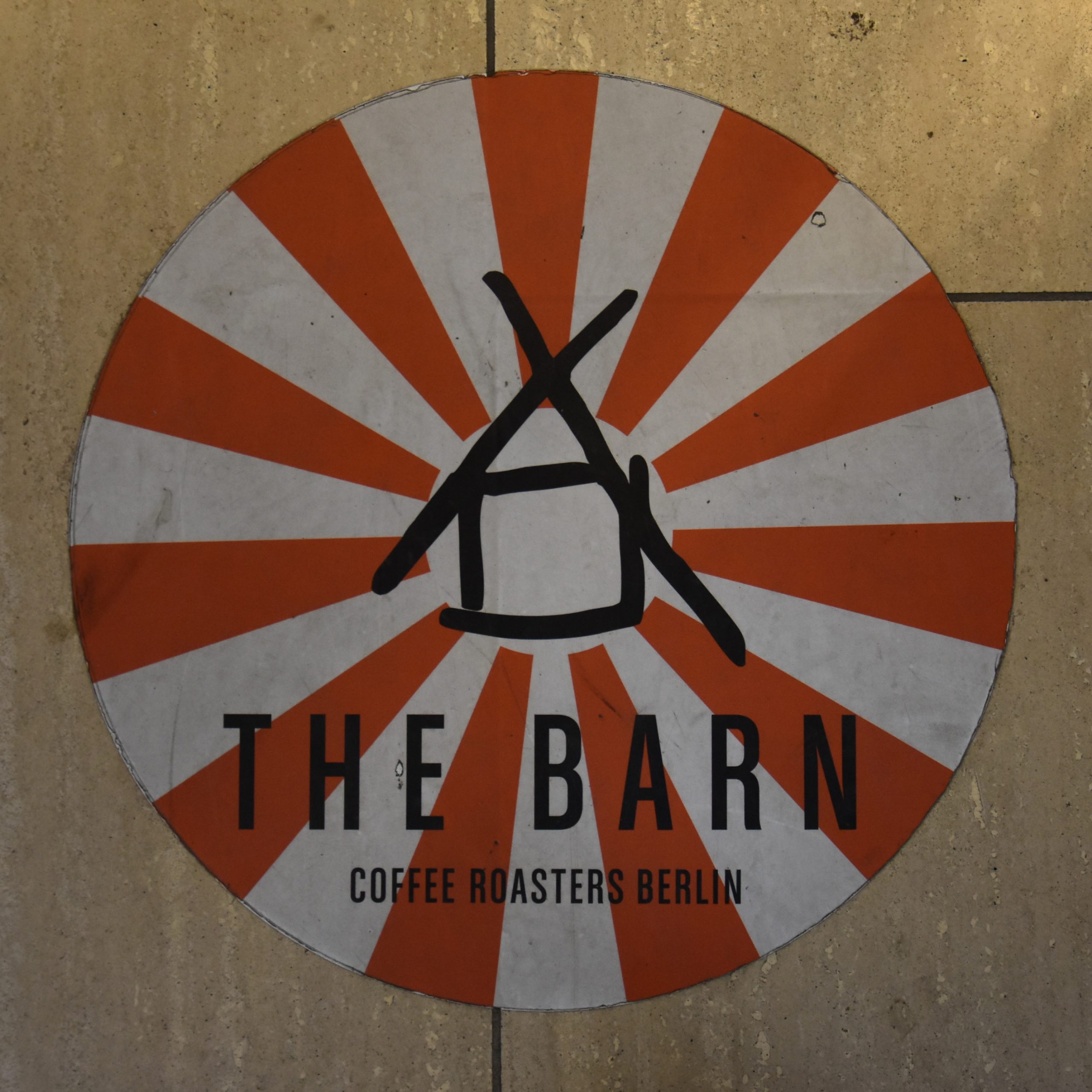 Two rolled into one, the minimalist logo of The Barn overlaid on the red and white stripped awning of Café Kanzler.