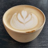 A flat white in a handleless ceramic cup at Public Space, Amsterdam.