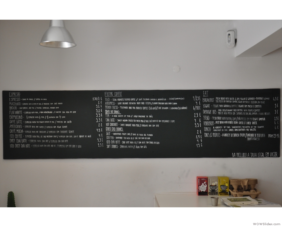 The menu is on the left-hand wall, to the left of the counter.
