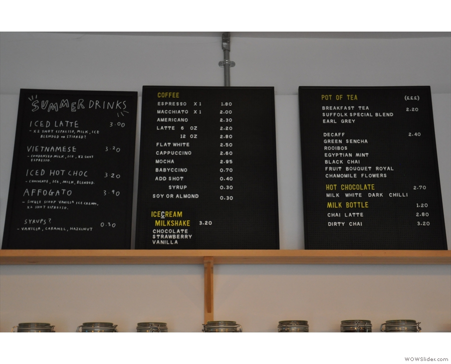 The coffee and hot drinks menus are on the wall behind the counter.