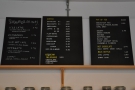 The coffee and hot drinks menus are on the wall behind the counter.