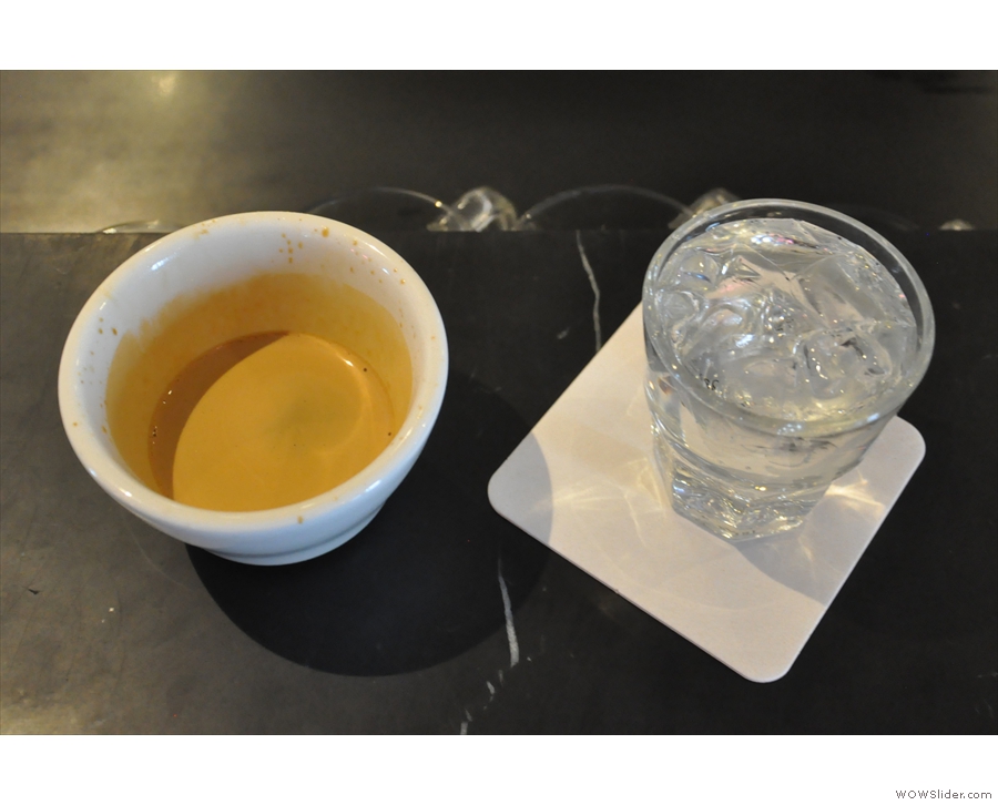 My resulting espresso, served in a handleless cup with a glass of water as standard.