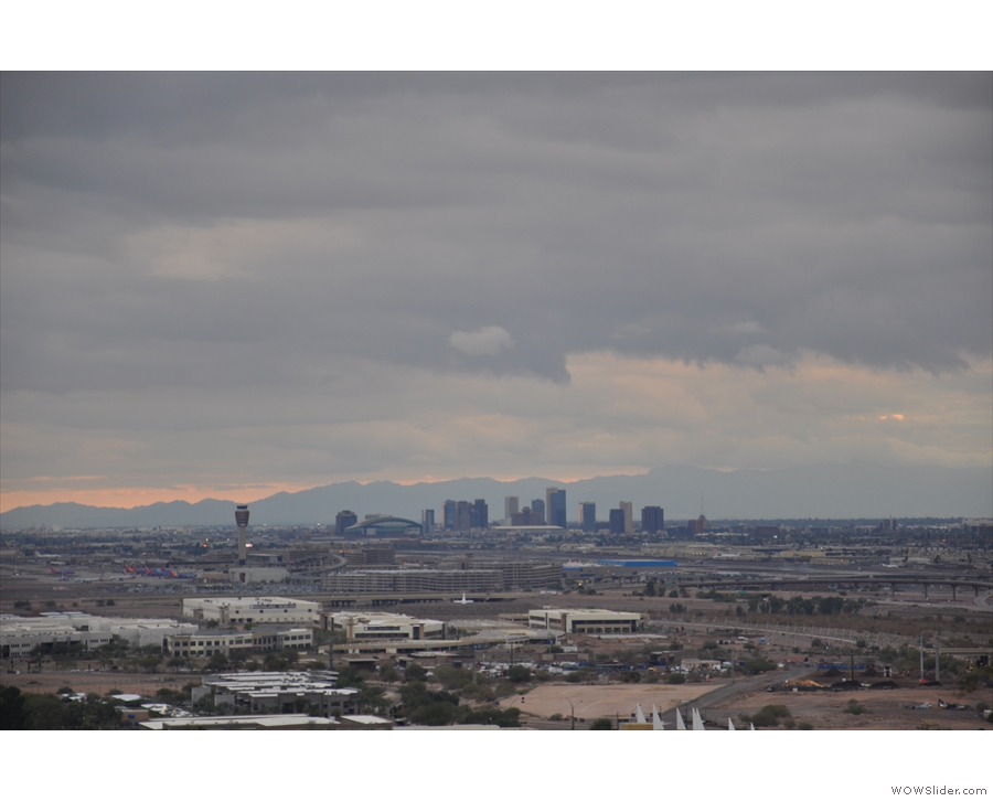 Downtown Phoenix with the sun setting behind the clouds/mountains to the west.